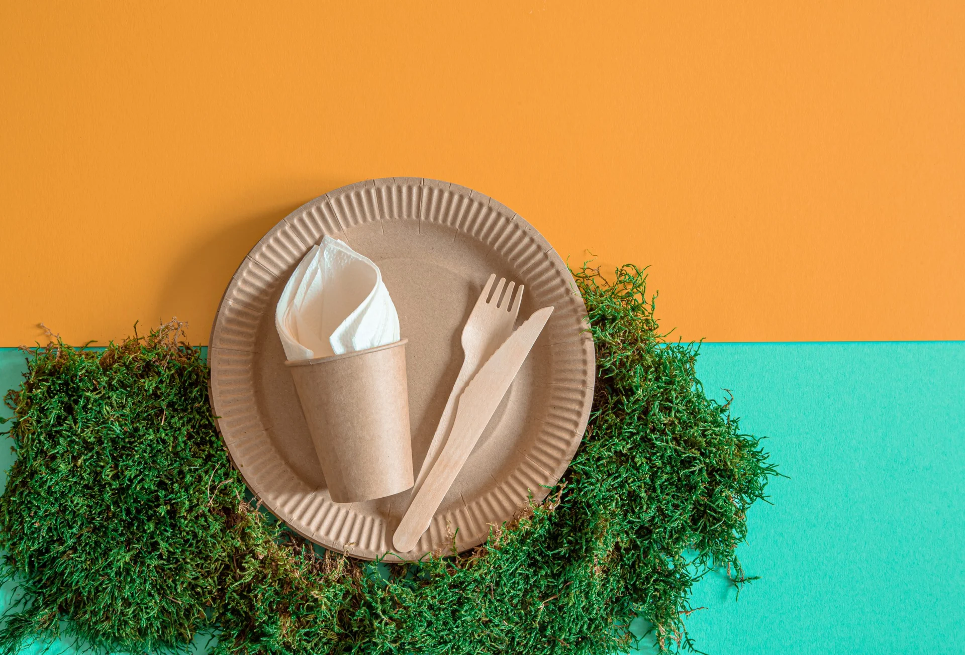 ECO craft paper tableware. Paper cups, plates, bag, fast food containers and wooden Cutlery with cornstarch on a colored orange-blue background. Recycling or the concept of zero waste. The view from the top.