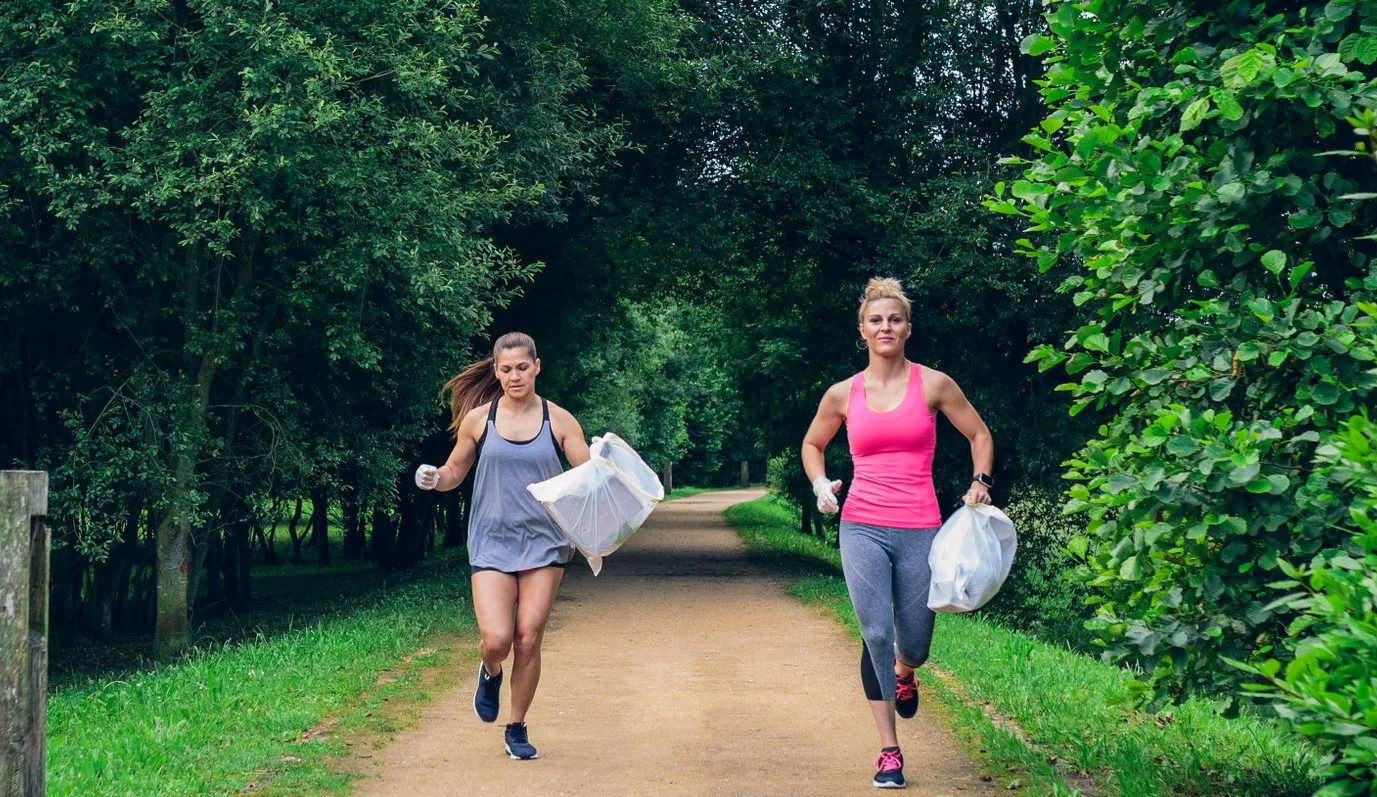 Two girls picking up trash while plogging outdoors